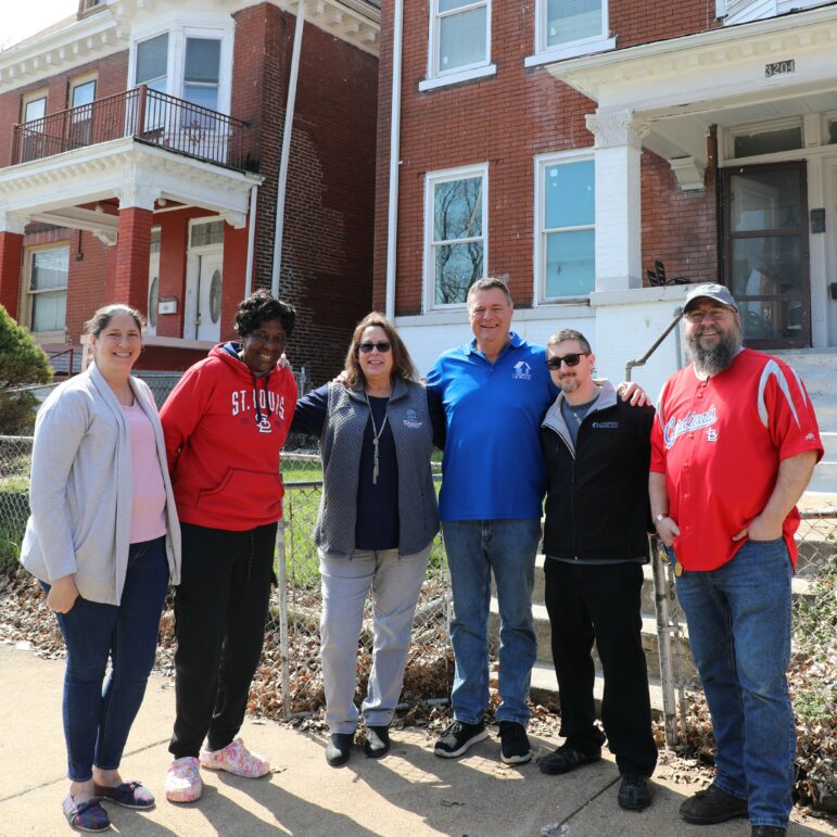 Representatives from a window company meet with a 100 Neediest Cases' recipient in front of their home.